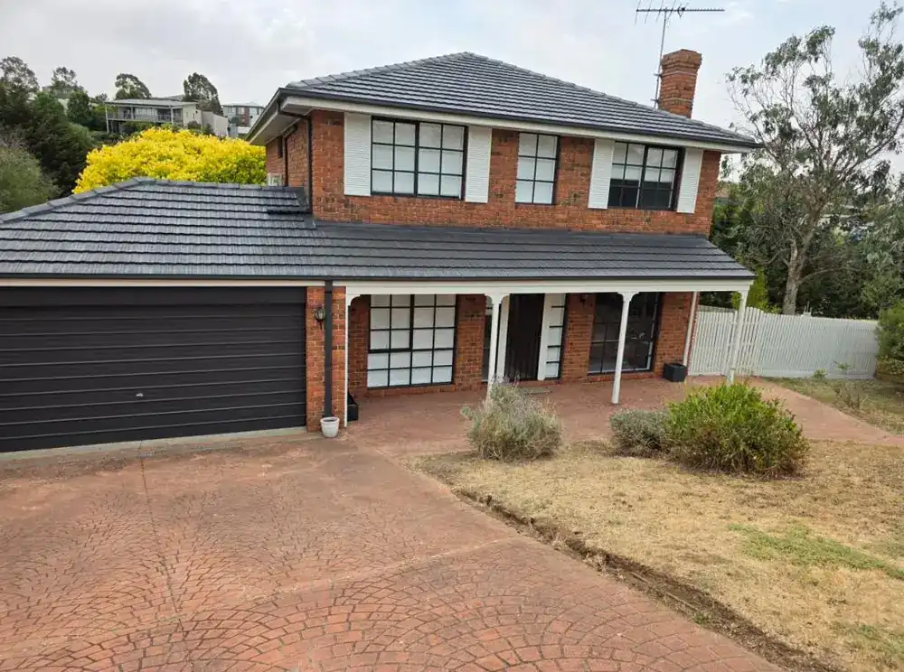 Two-storey brick home with a repainted dark garage door and trims