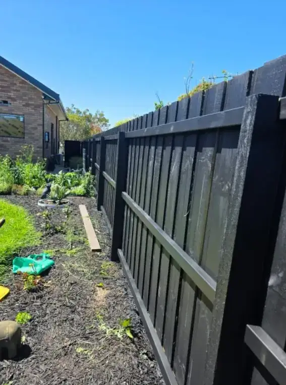 Charcoal-painted timber fence alongside a vegetable garden