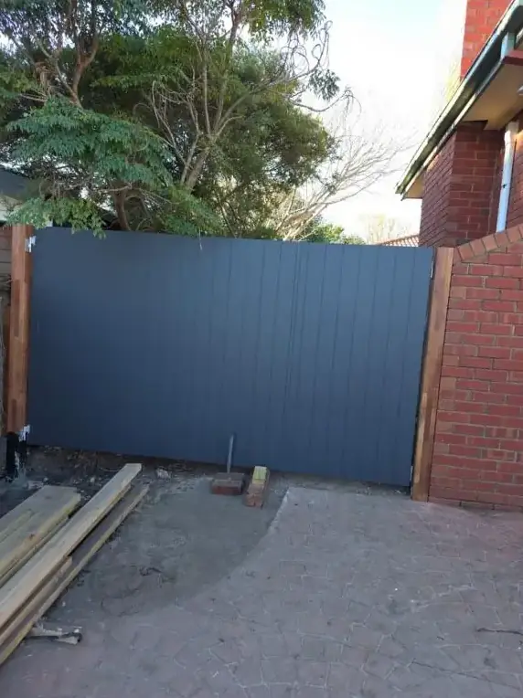 Grey Colorbond fence panel painted against a brick wall