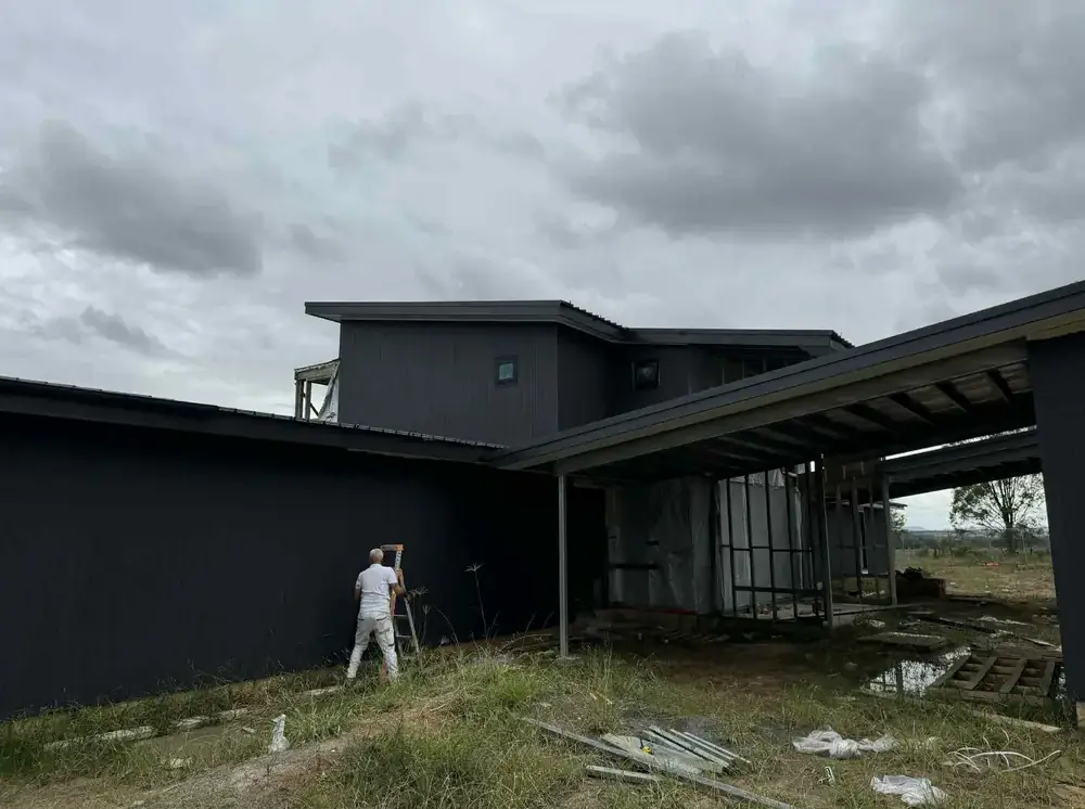 Painter spray-painting the exterior of a large modern building
