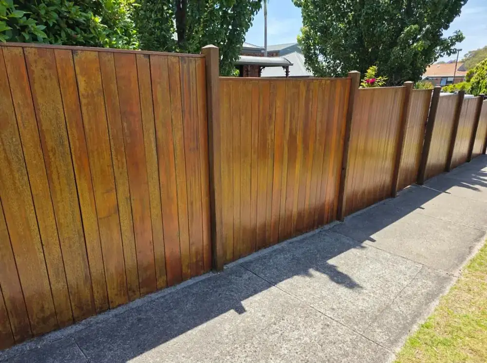 Stained timber paling fence running along a driveway