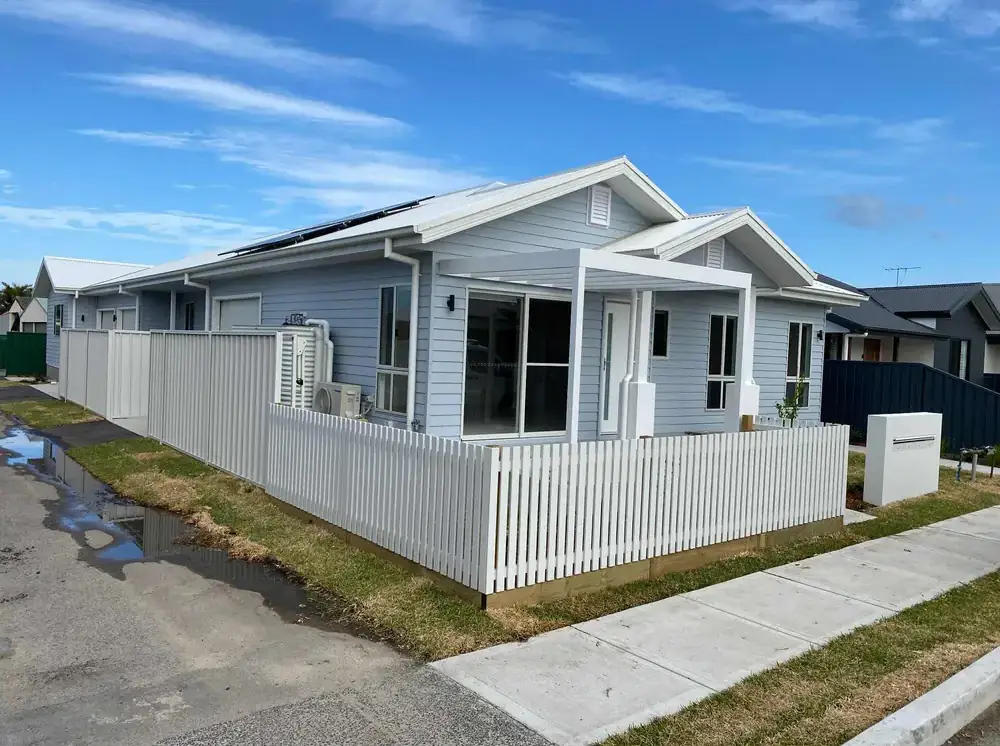 White weatherboard home and picket fence after an exterior repaint