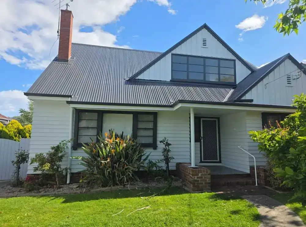 Repainted white weatherboard home with a metal roof